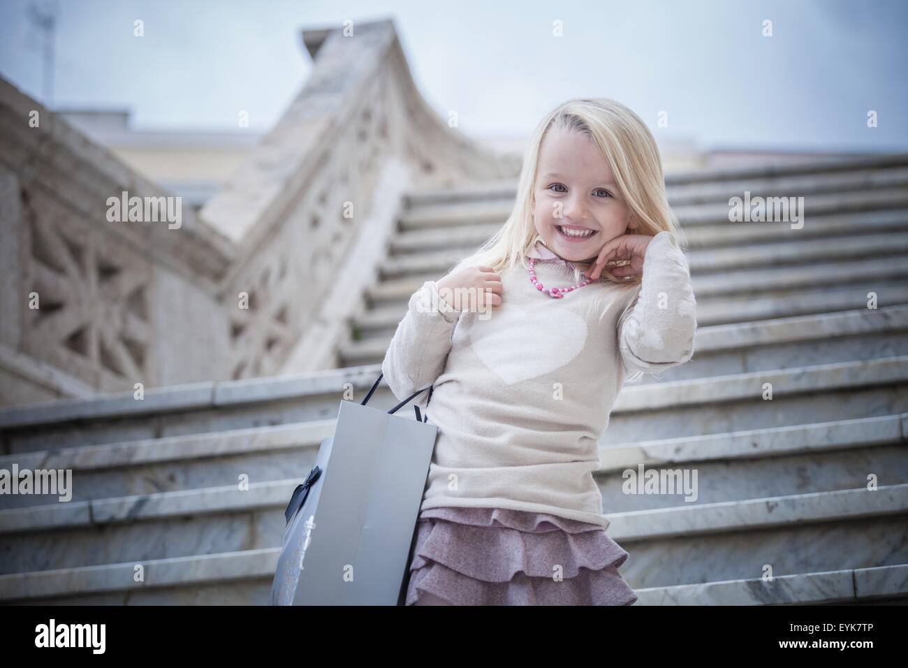 Portrait of young girl on stairway carrying shopping bag, Cagliari, Sardinia, Italy Stock Photo