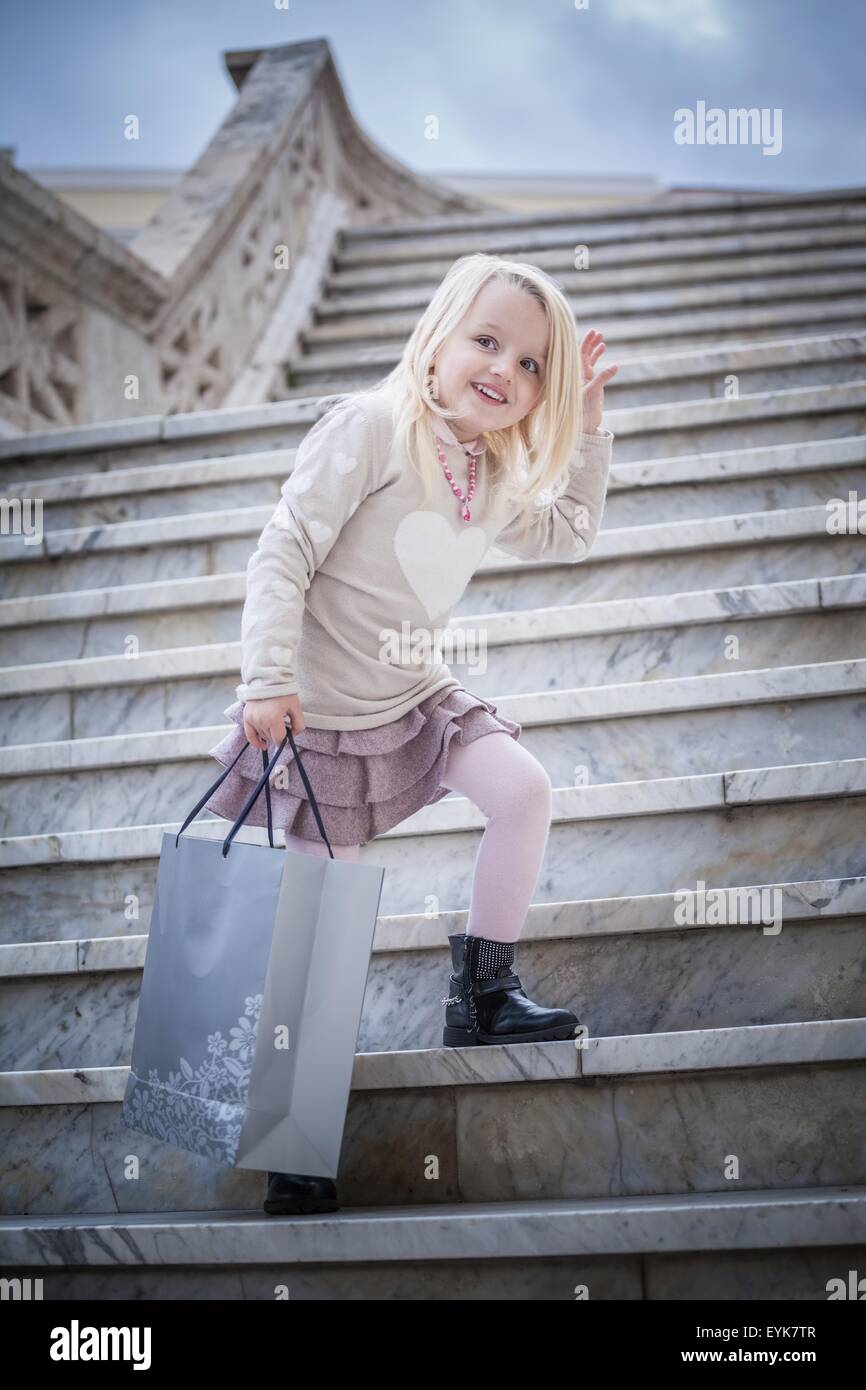 Portrait of young girl posing on stairway carrying shopping bag, Cagliari, Sardinia, Italy Stock Photo
