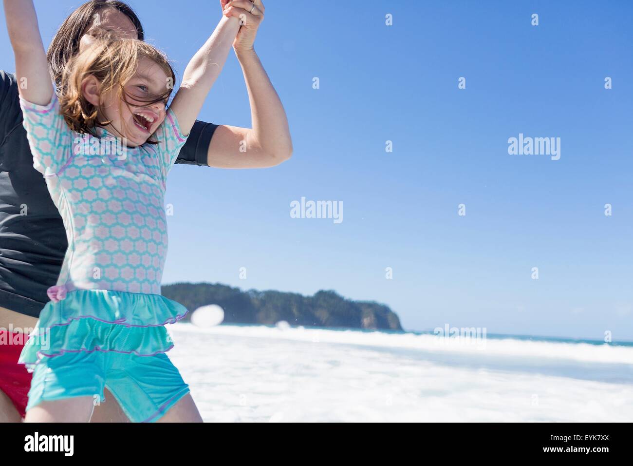 Mother and daughter jumping in sea, Hot Water Beach, Bay of Islands, New Zealand Stock Photo