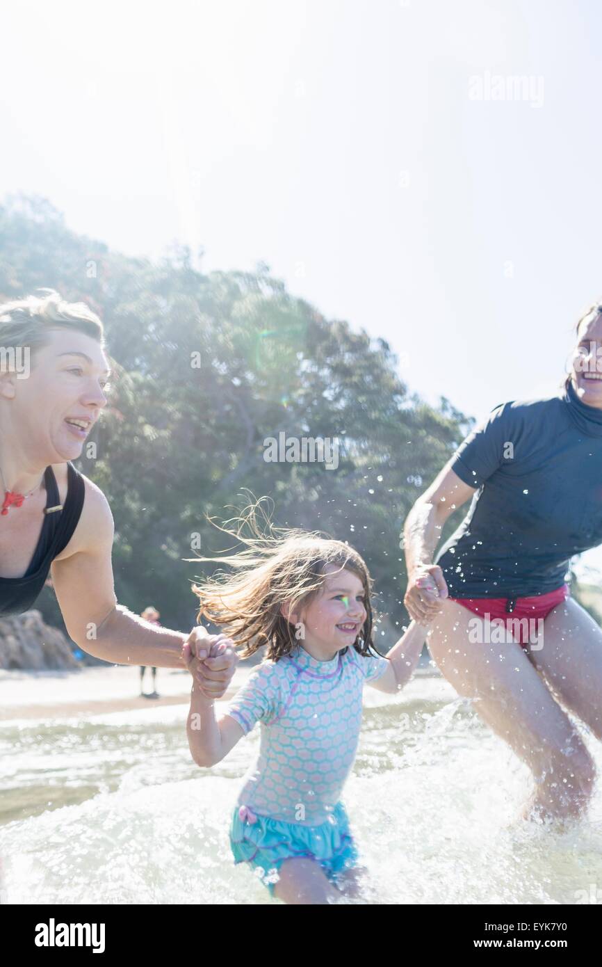 Two women and girl running into sea, Hot Water Beach, Bay of Islands, New Zealand Stock Photo