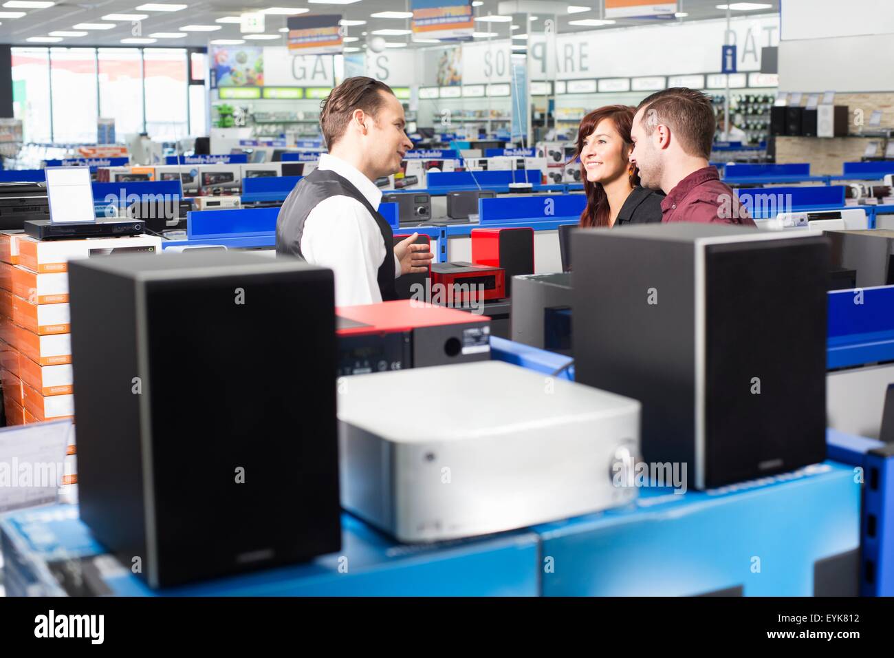 Sales assistant advising couple in electronics store Stock Photo