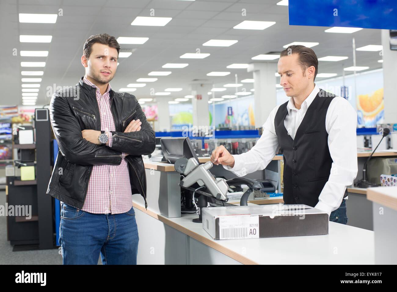 Unsure shopper paying with credit card in electronics store Stock Photo
