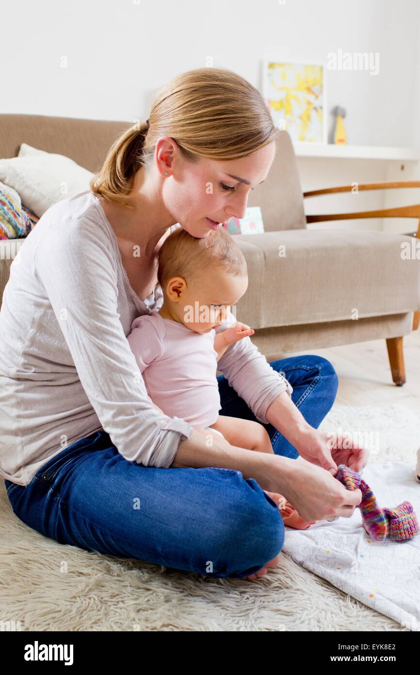 Mother putting socks on baby girl Stock Photo
