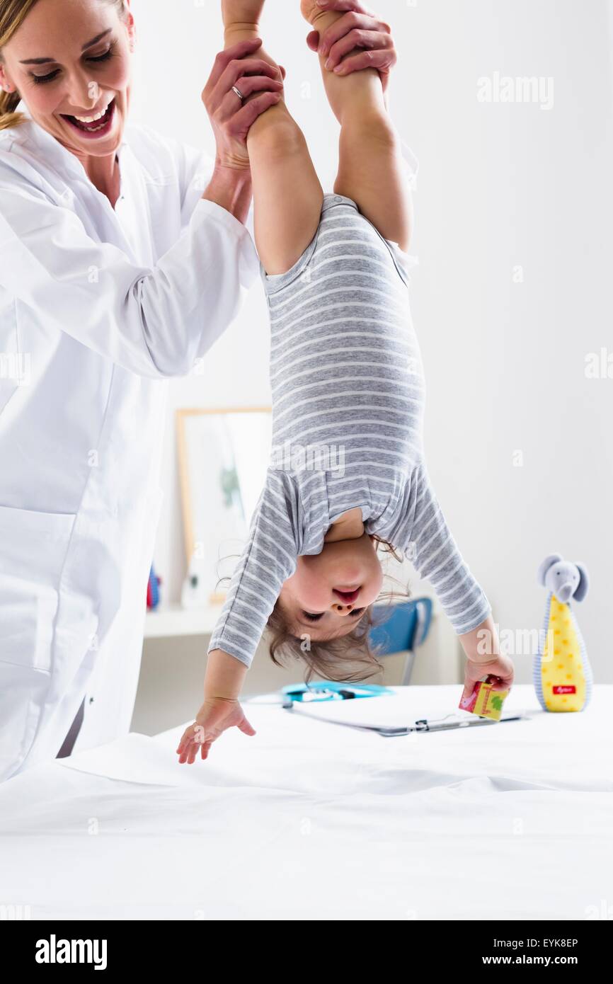 Paediatrician holding baby boy upside-down Stock Photo