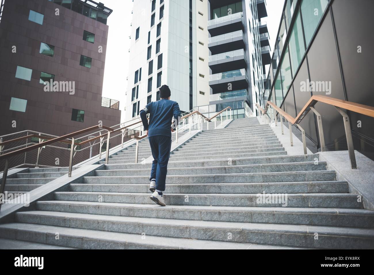 Rear view of young male runner running up city stairs Stock Photo