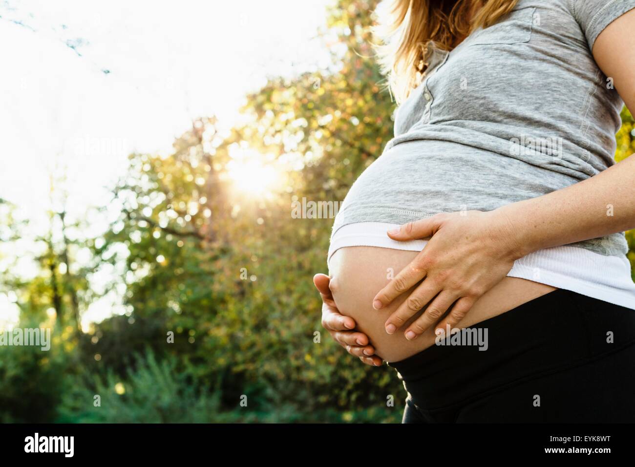 Pregnant woman holding belly, outdoors, mid section Stock Photo Alamy