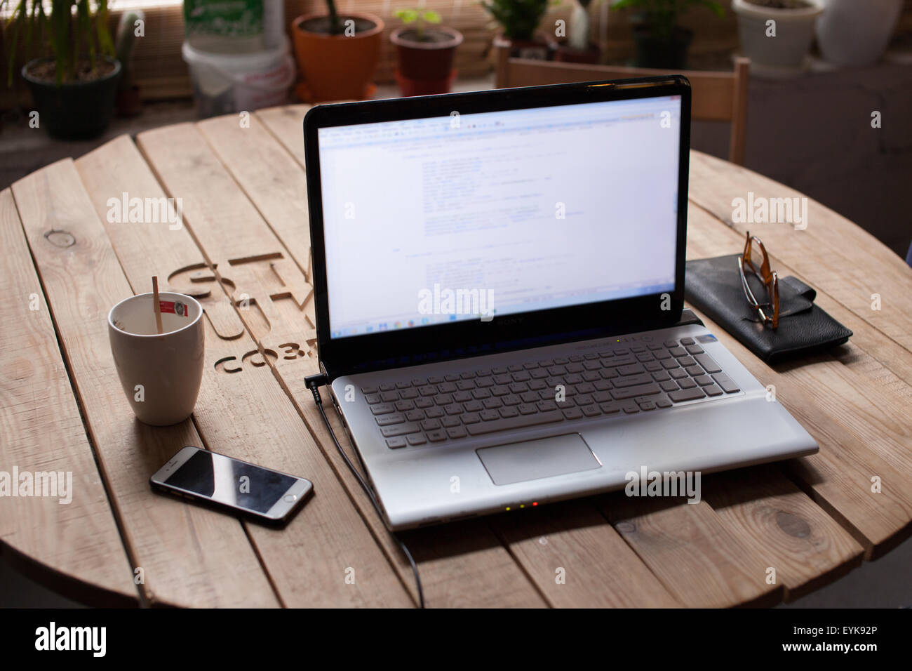 Wooden table with laptop, glasses, wallet and cup of coffee Stock Photo