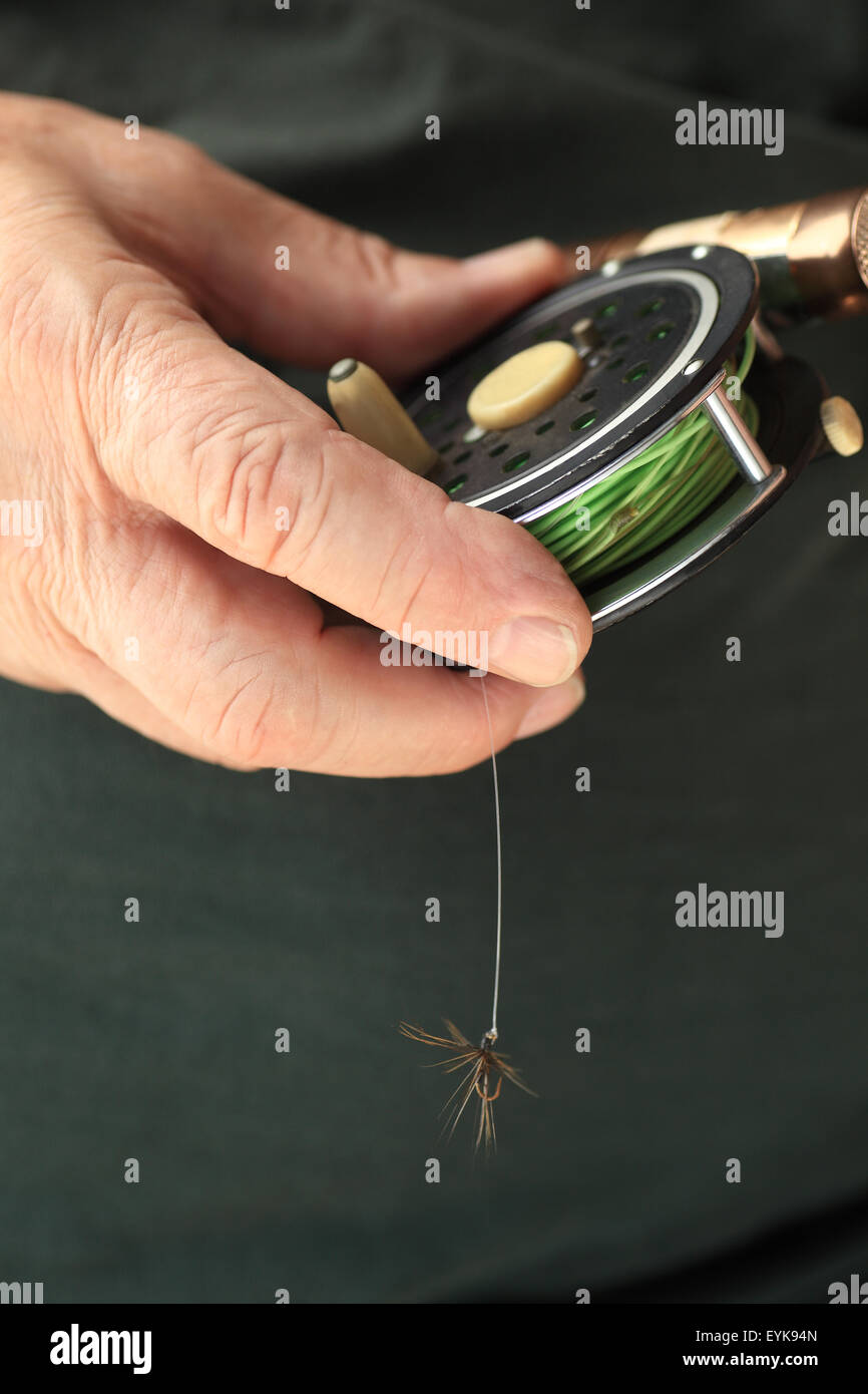 A man holds a fly fishing rod and reel with fly attached, copy space included Stock Photo