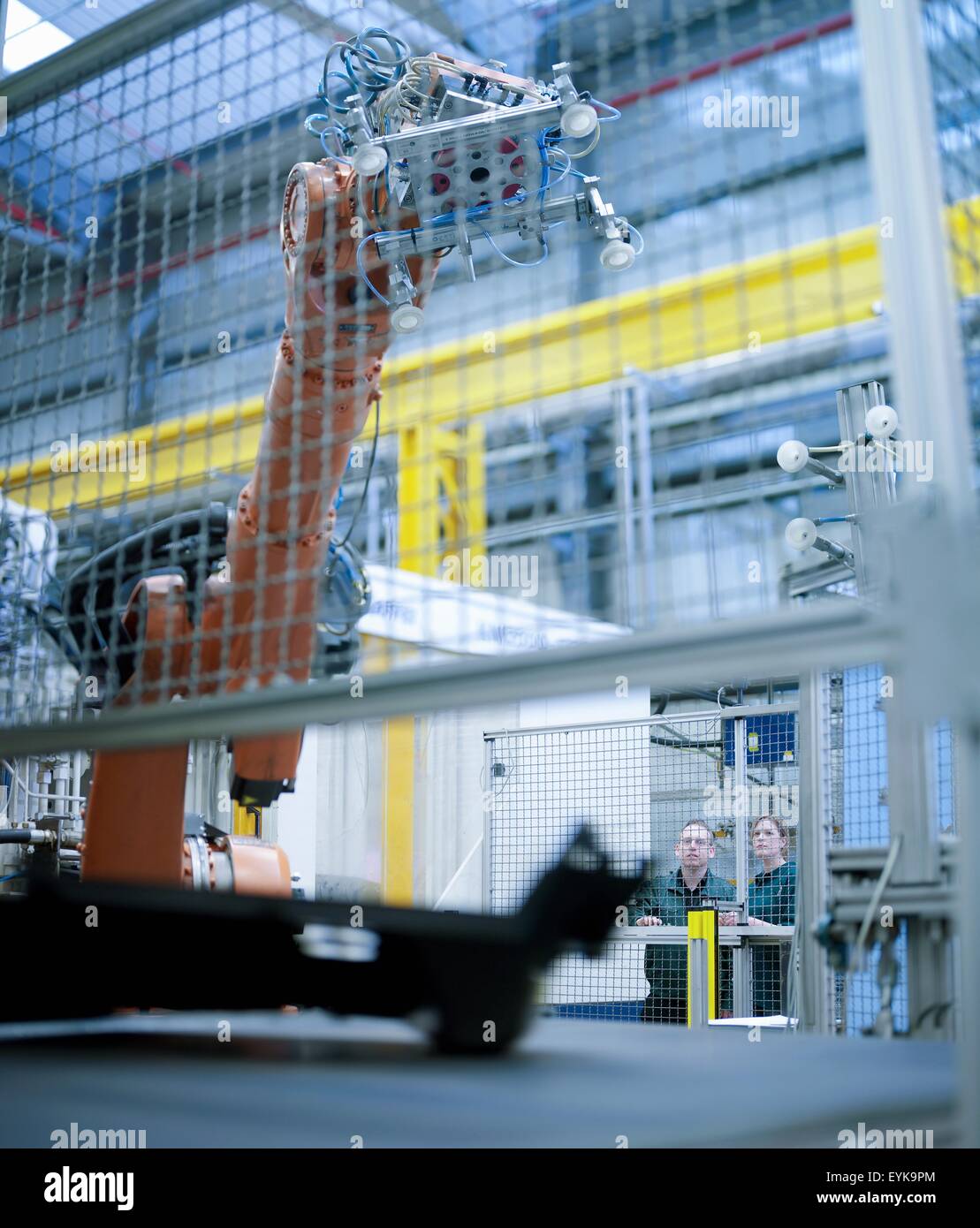 Workers watching robot perform tasks in factory Stock Photo