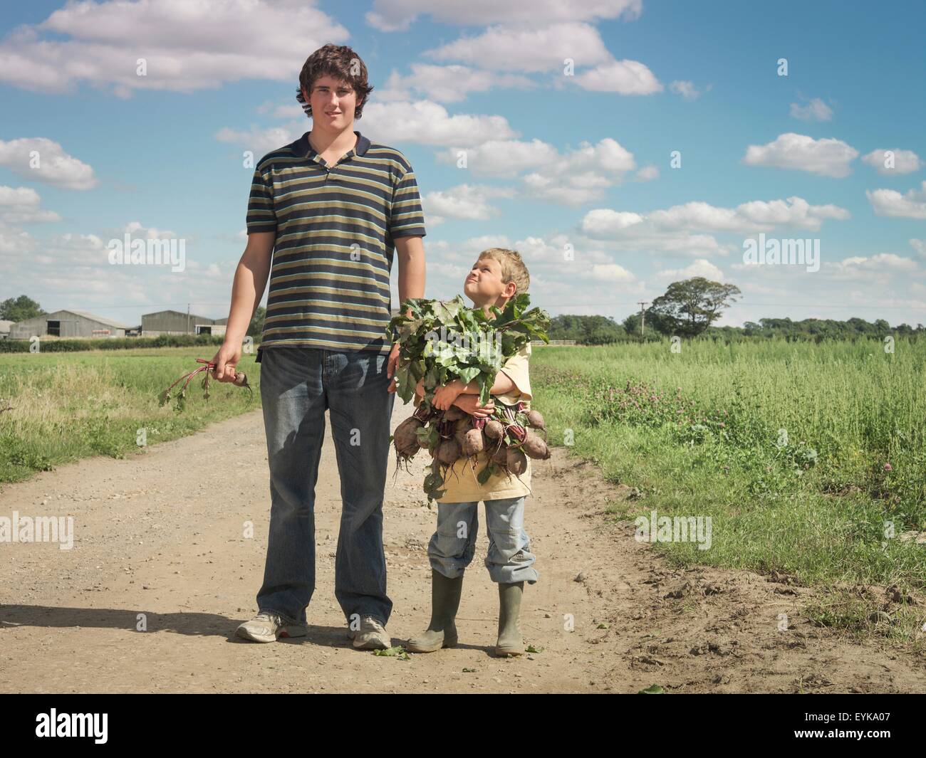 Tall and smaller farmers sons carrying armful of organic beetroot Stock Photo