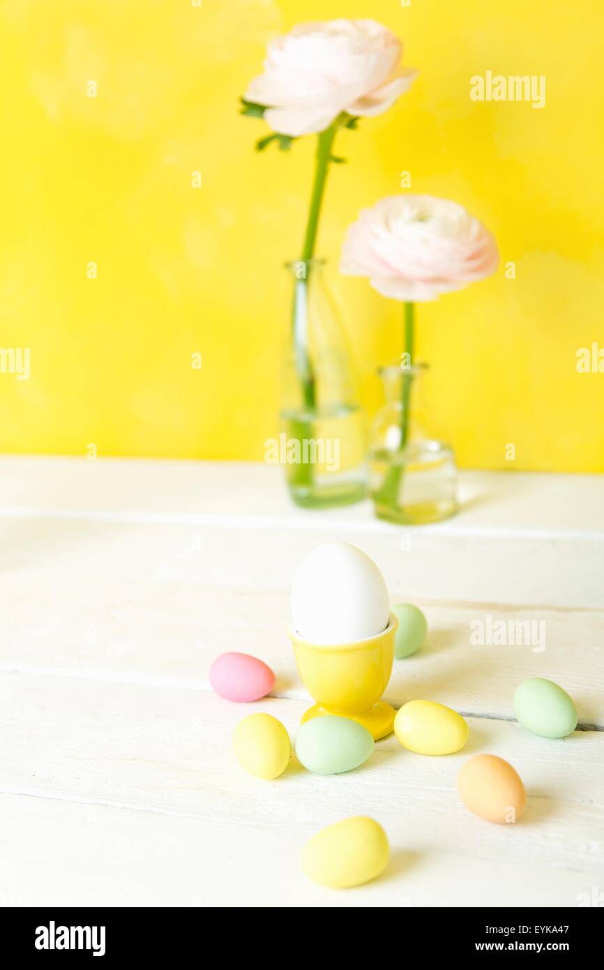 Still life of cut flowers in bottles and confectionery Easter eggs Stock Photo