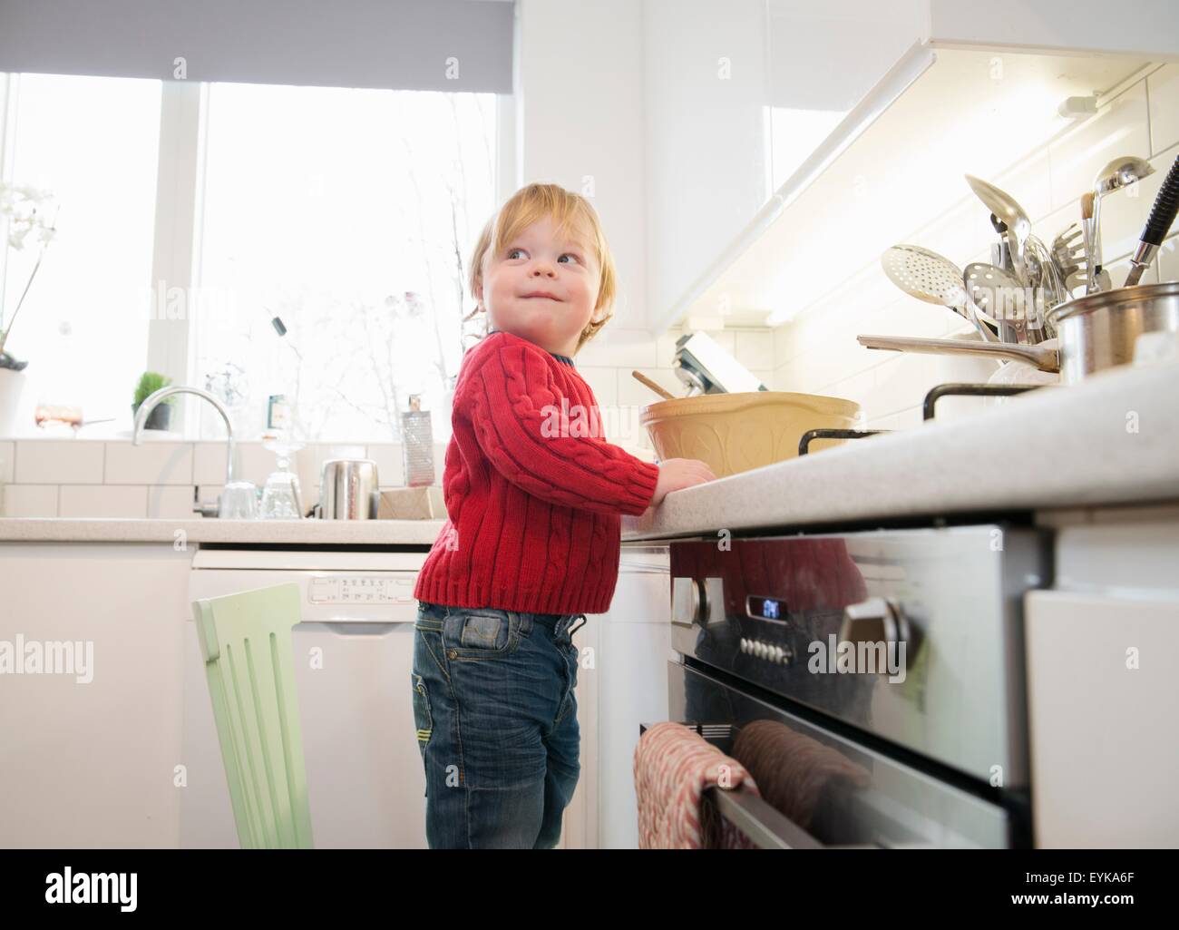 Boy standing on chair in kitchen Stock Photo