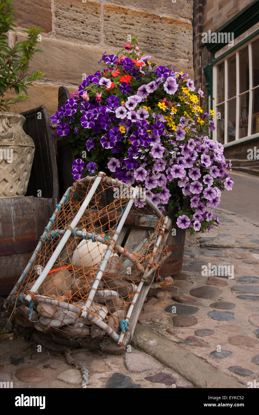 Lobster pot and planter with petunias decorating a street corner in Robin Hoods Bay, near Whitby North Yorkshire, England UK. Stock Photo