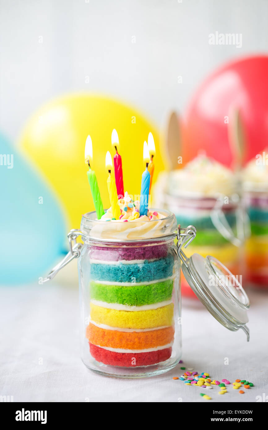 Rainbow layer cake in a jar with birthday candles Stock Photo - Alamy