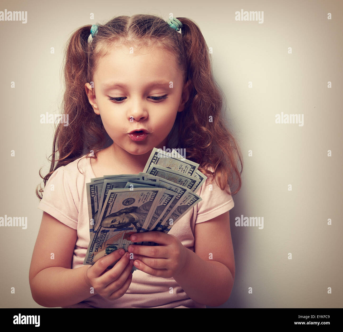 Fun grimacing kid girl looking and counting money in the hands. Vintage ...