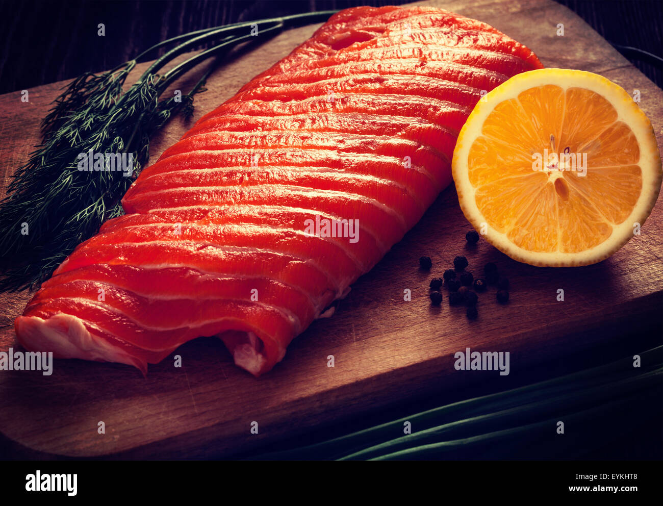 Vintage retro effect filtered hipster style image of fresh salmon piece on wooden cooking board with vegetables Stock Photo