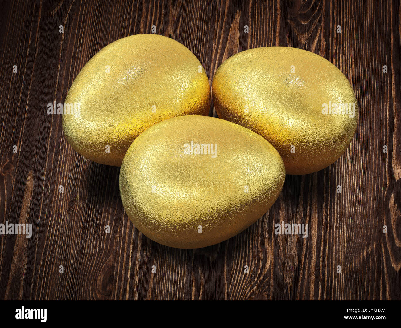 Three golden Easter eggs isolated on wooden background Stock Photo