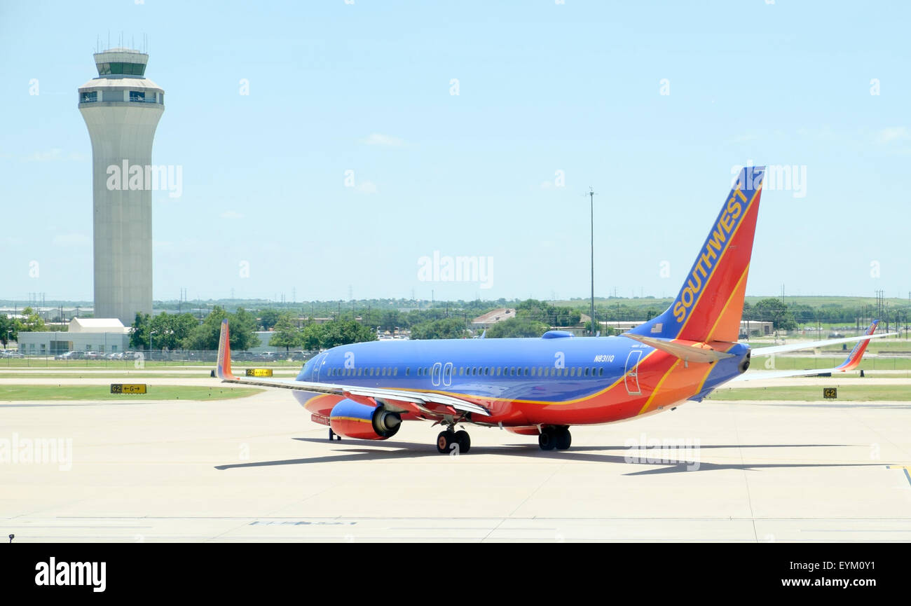 Southwest Airlines Boeing 737 jet airplane taxiing for takeoff with air traffic control tower in background at Austin Texas Bergstrom Airport Stock Photo