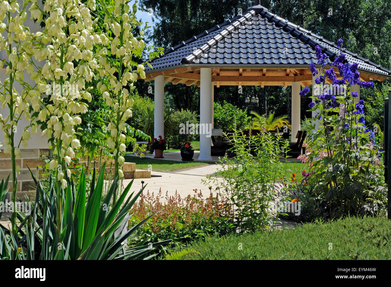 Romantic country house garden with attractive jewellery shrubs, yucca, larkspur, garden pavilion, Stock Photo