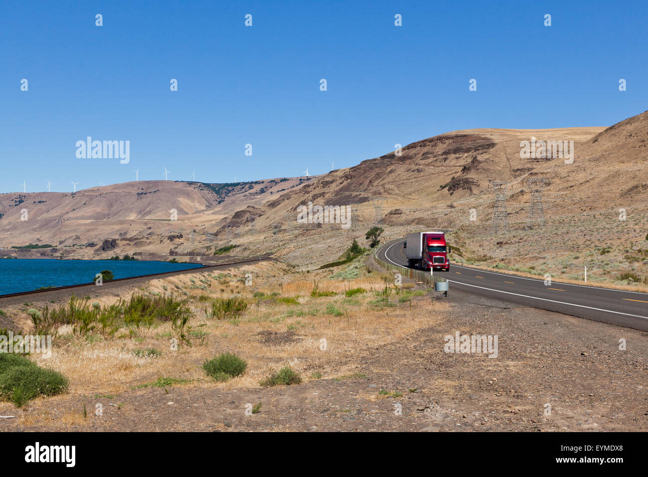 A two lane road with a red semi truck driving through the Columbia River Gorge on the Washington State side in summer. Stock Photo