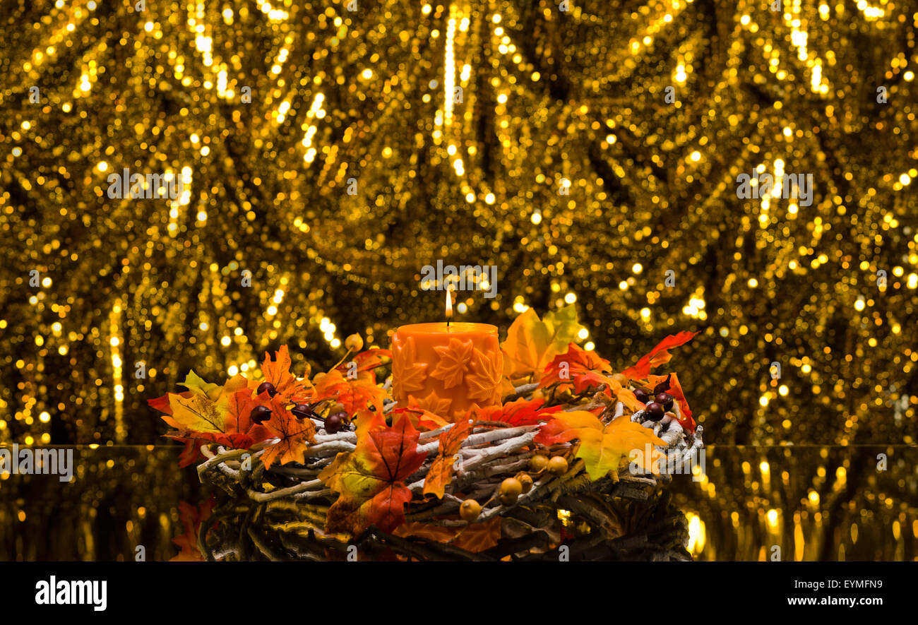 Orange candle in autumn Christmas setting in front of a golden background Stock Photo