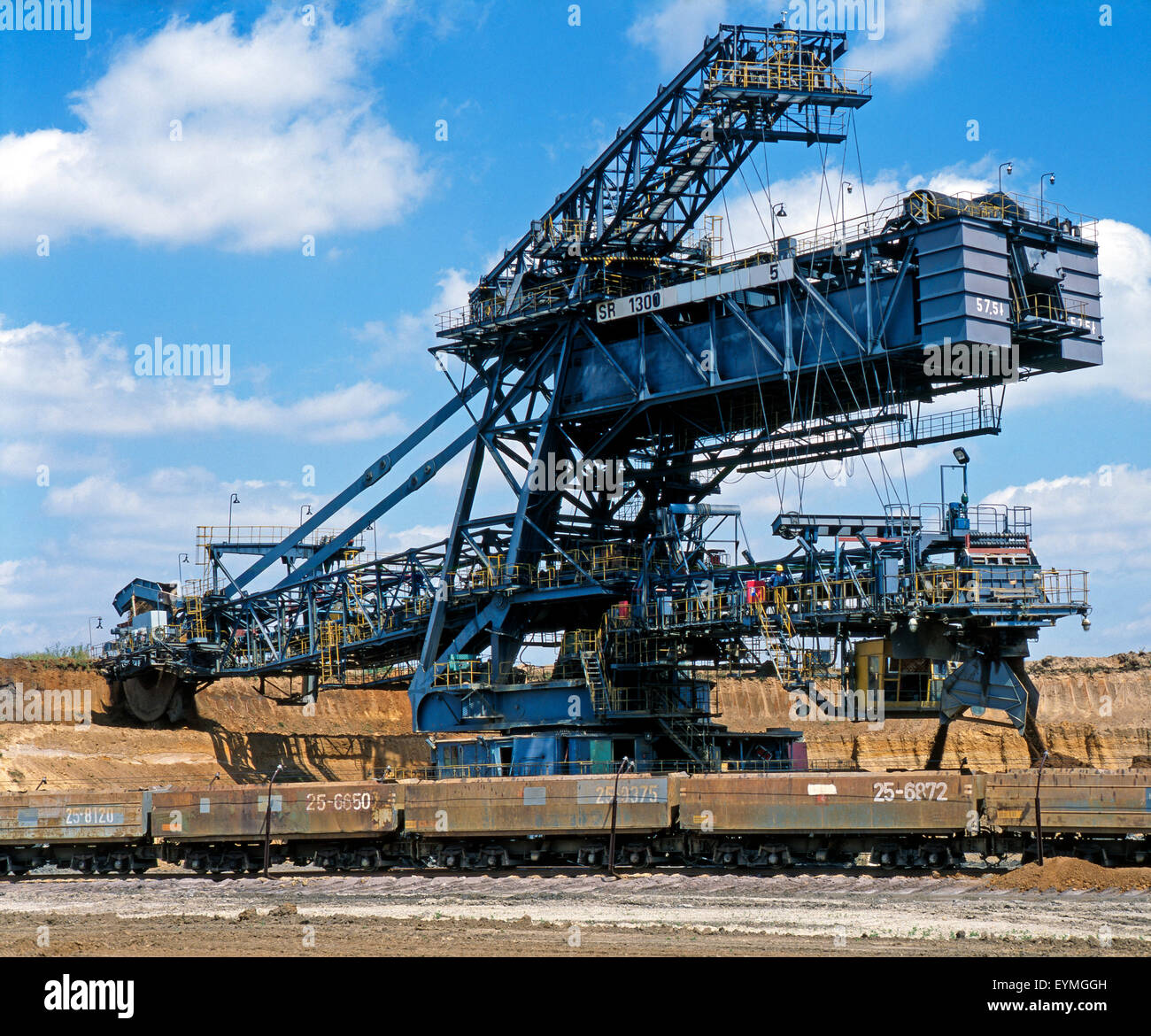 Overburden conveyor bridge at brown coal opencast mining loads tipping wagons near overburden Stock Photo