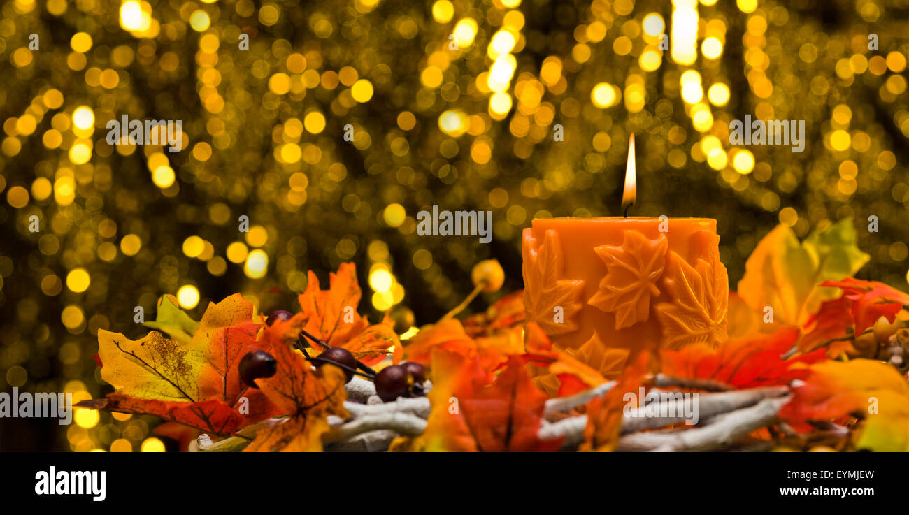 Orange candle in autumn Christmas setting in front of a golden background Stock Photo