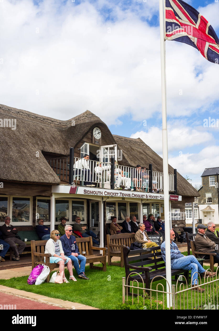 The cricket pavilion with spectators and players watching a match at Sidmouth Cricket Club in Devon. Stock Photo