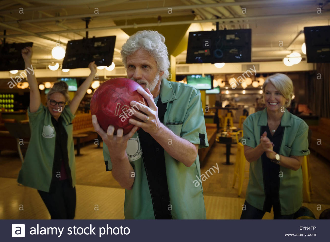 Teammates cheering man bowling at bowling alley Stock Photo