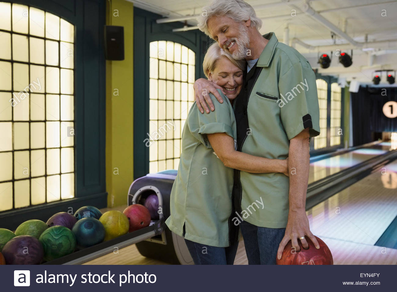 Couple in bowling shirts hugging at bowling alley Stock Photo