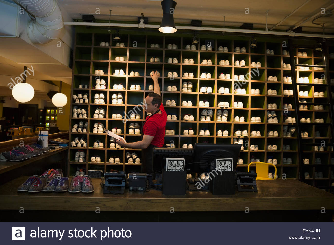 Worker with clipboard reaching for bowling shoes Stock Photo