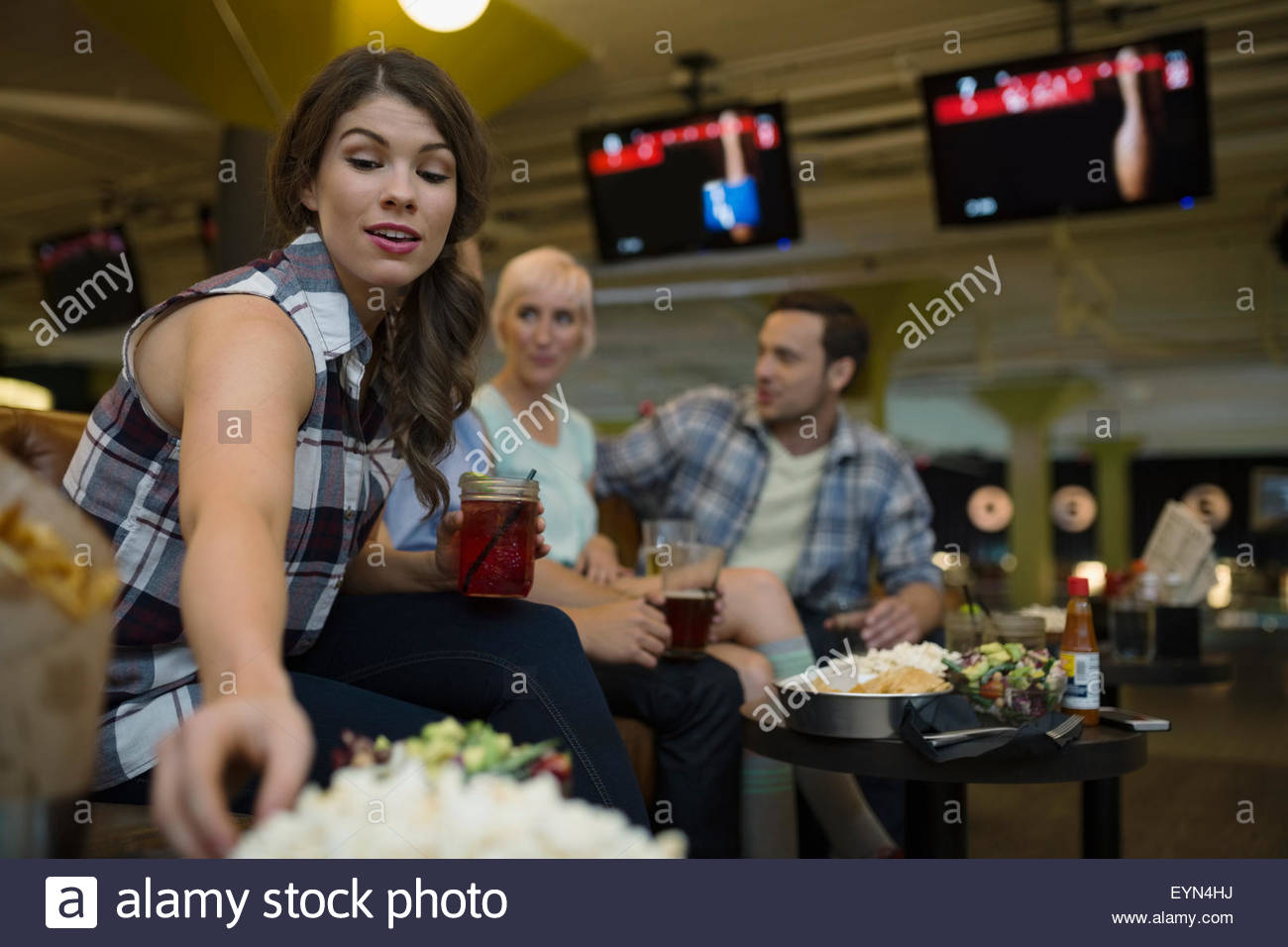 Friends eating and drinking at bowling alley Stock Photo