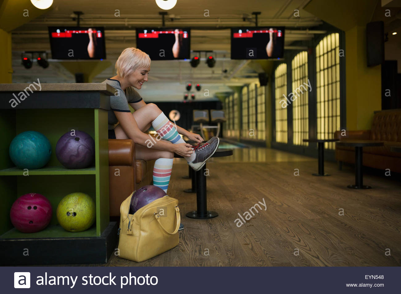 Young woman putting on bowling shoes bowling alley Stock Photo Alamy