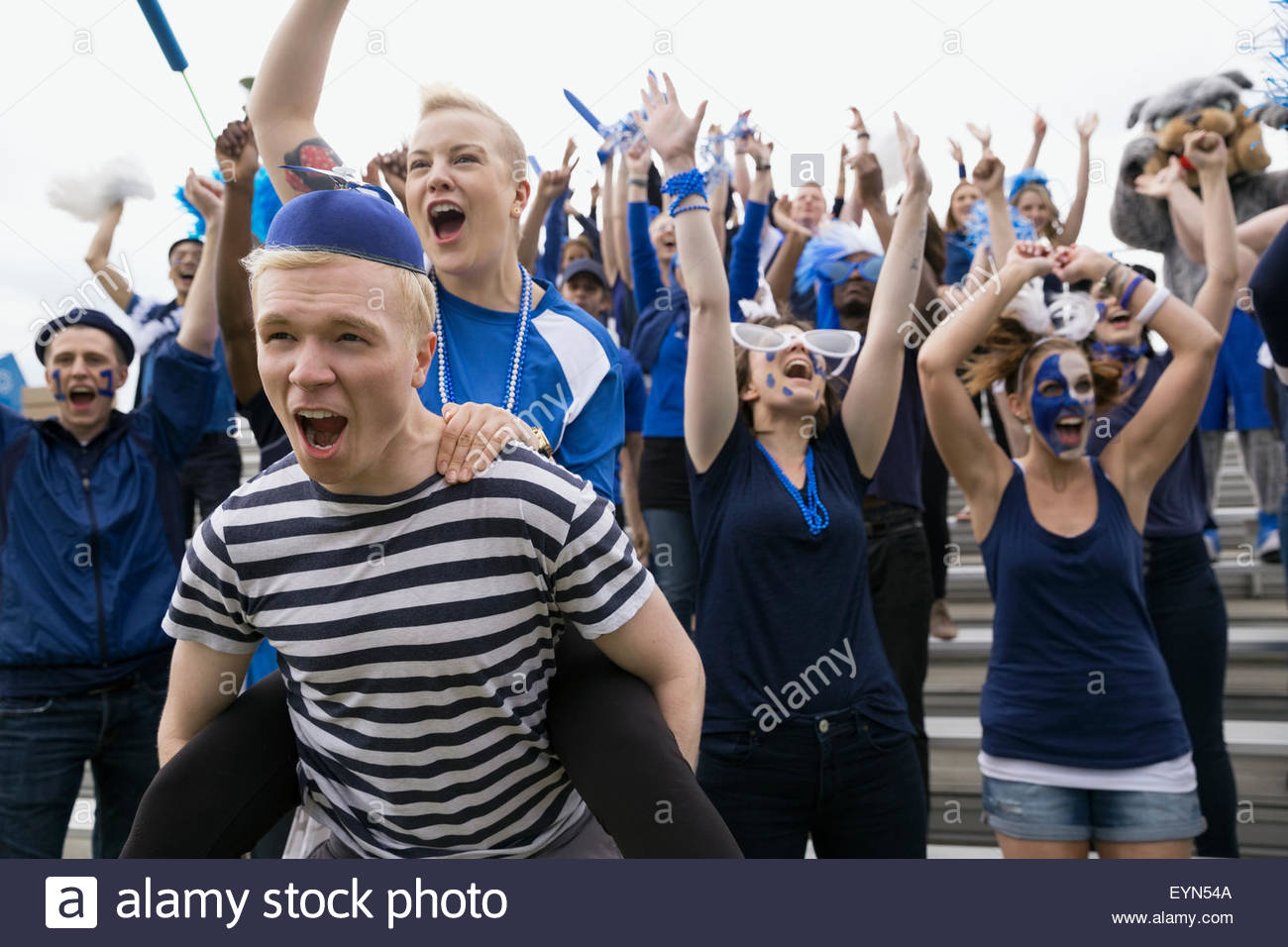 Enthusiastic fans in blue cheering bleachers sports event Stock Photo