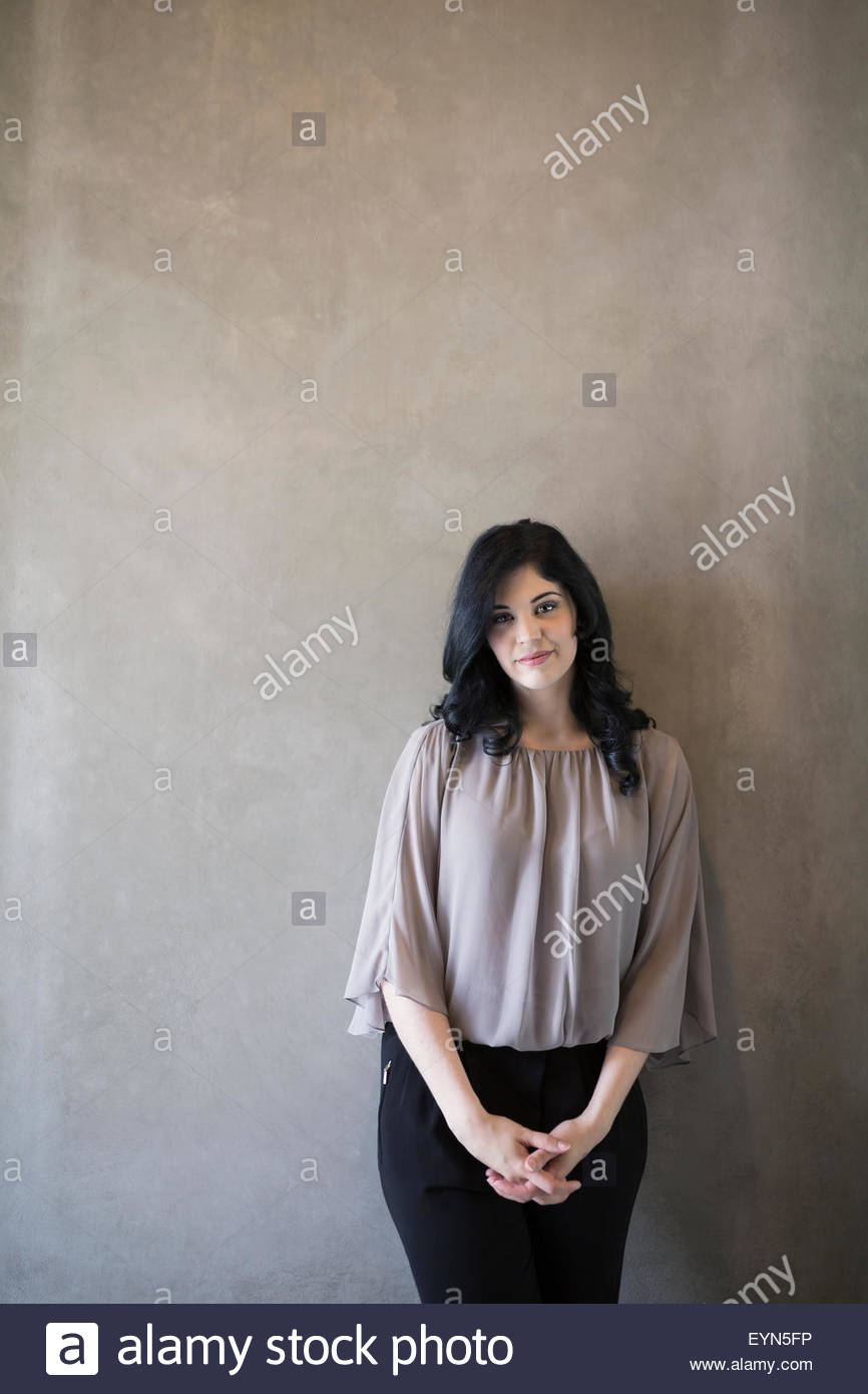 Portrait confident woman with hands clasped gray background Stock Photo