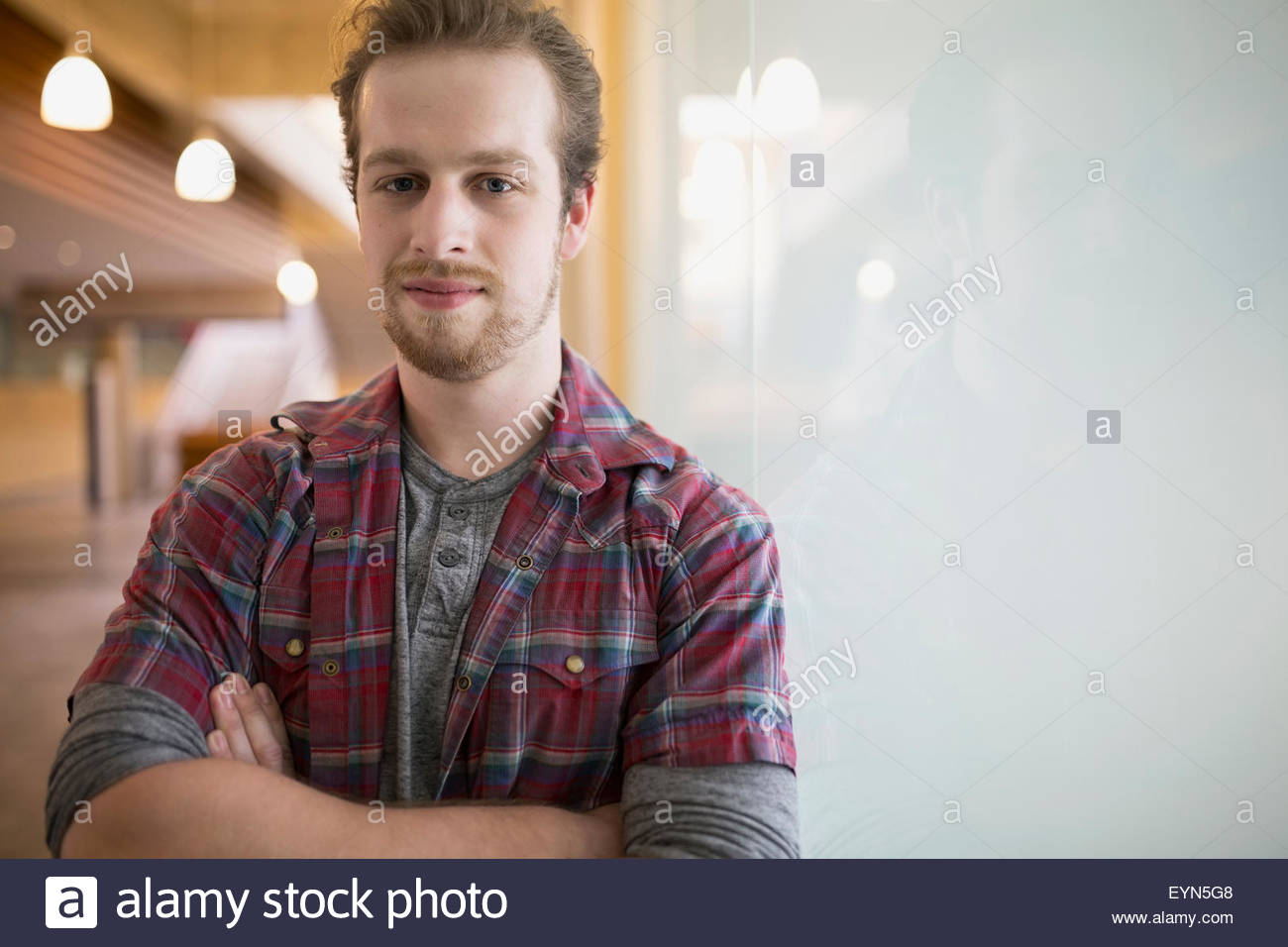Portrait confident man with arms crossed at frosted glass Stock Photo