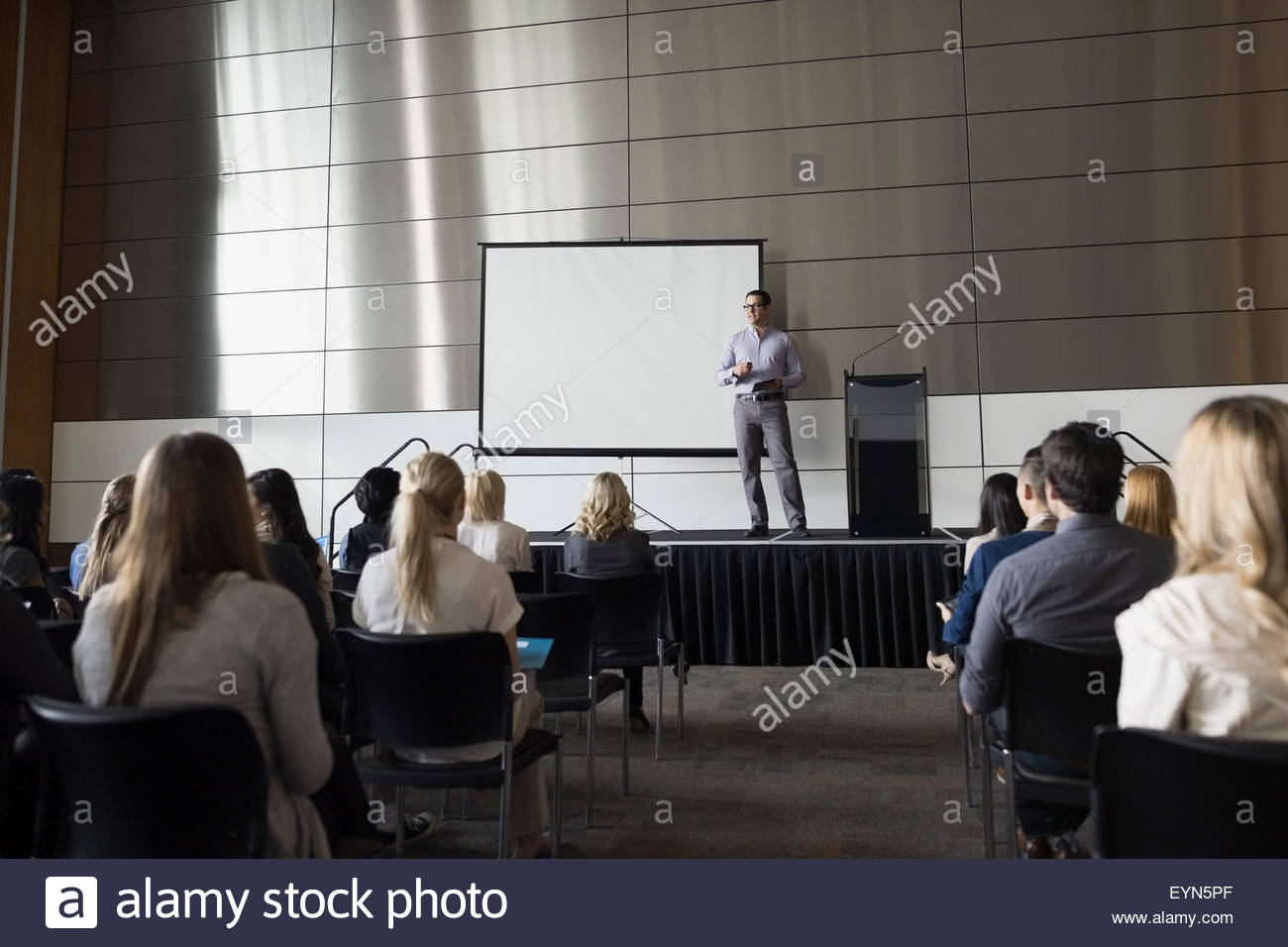Professor on stage speaking to students in auditorium Stock Photo