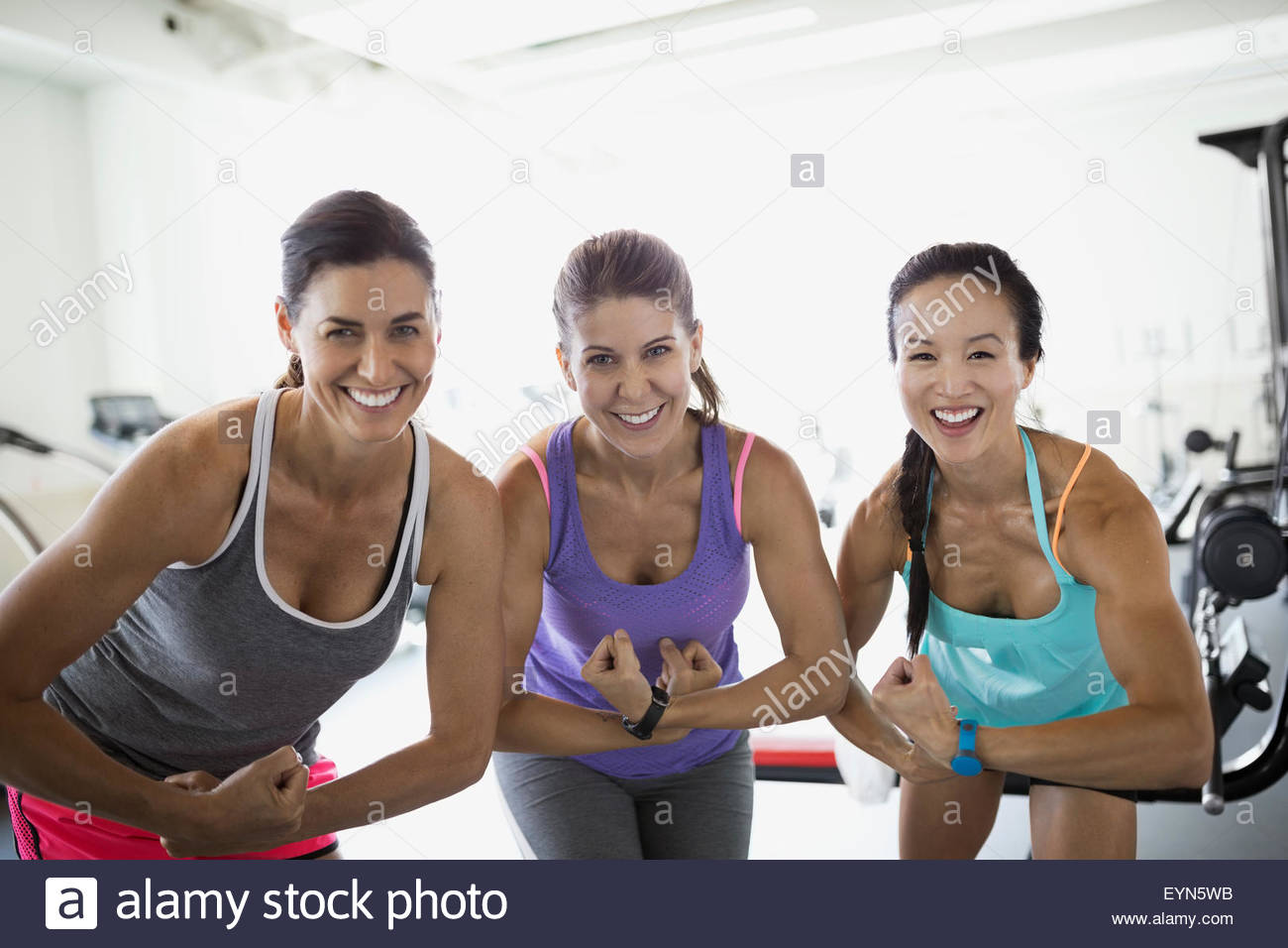Portrait confident women flexing muscles at gym Stock Photo