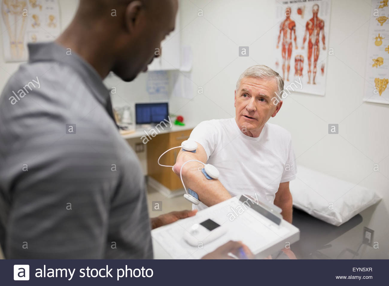 Physical therapist talking to patient with electrodes arm Stock Photo