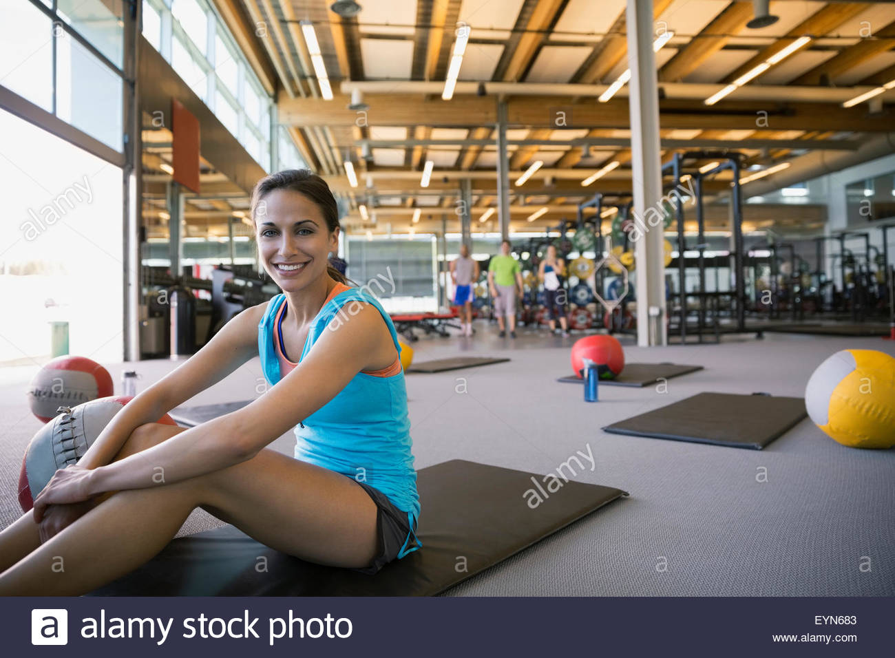 Portrait smiling woman on exercise mat in gym Stock Photo