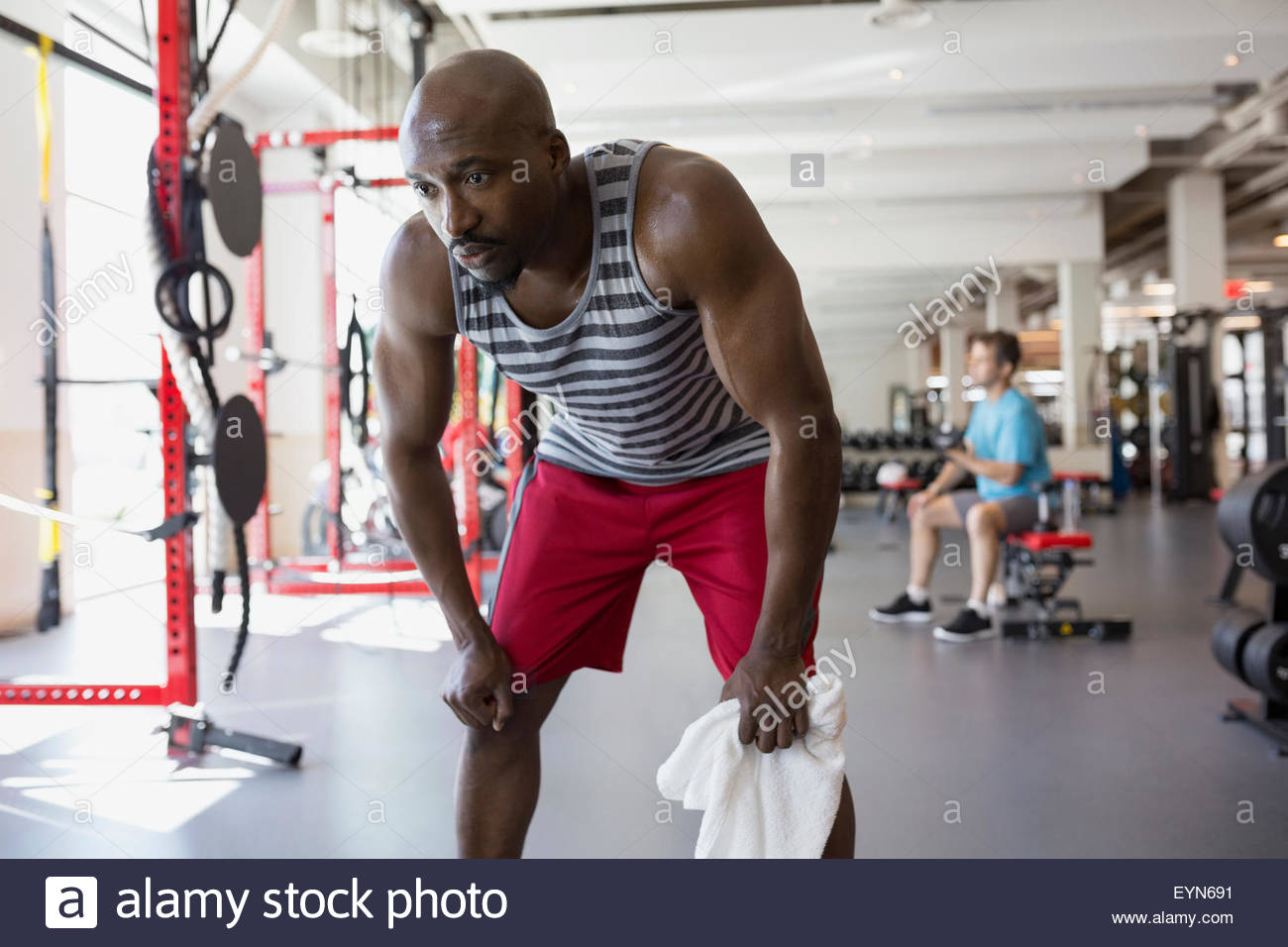 Tired man resting with hands on knees at gym Stock Photo
