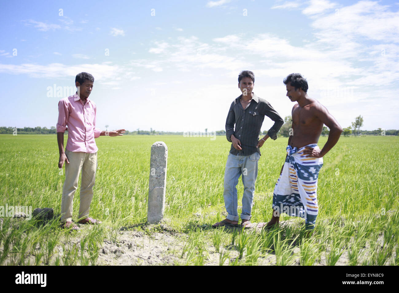 Bangladesh. 30th July, 2015. Pradip Barman (L), 26, with other two residence of Dalaha-Khagrabari stands in front of a pillar that indicates the boundary of Indian enclaves Dalaha-Khagrabari inside Bangladesh, Dalaha-Khagrabari in the Bangladeshi district of Panchagarh, on July 30, 2015. Bangladesh and India will this week finally swap tiny islands of land, ending one of the world's most difficult border disputes that has kept thousands of people in stateless limbo for almost 70 years. © Suvra Kanti Das/ZUMA Wire/Alamy Live News Stock Photo