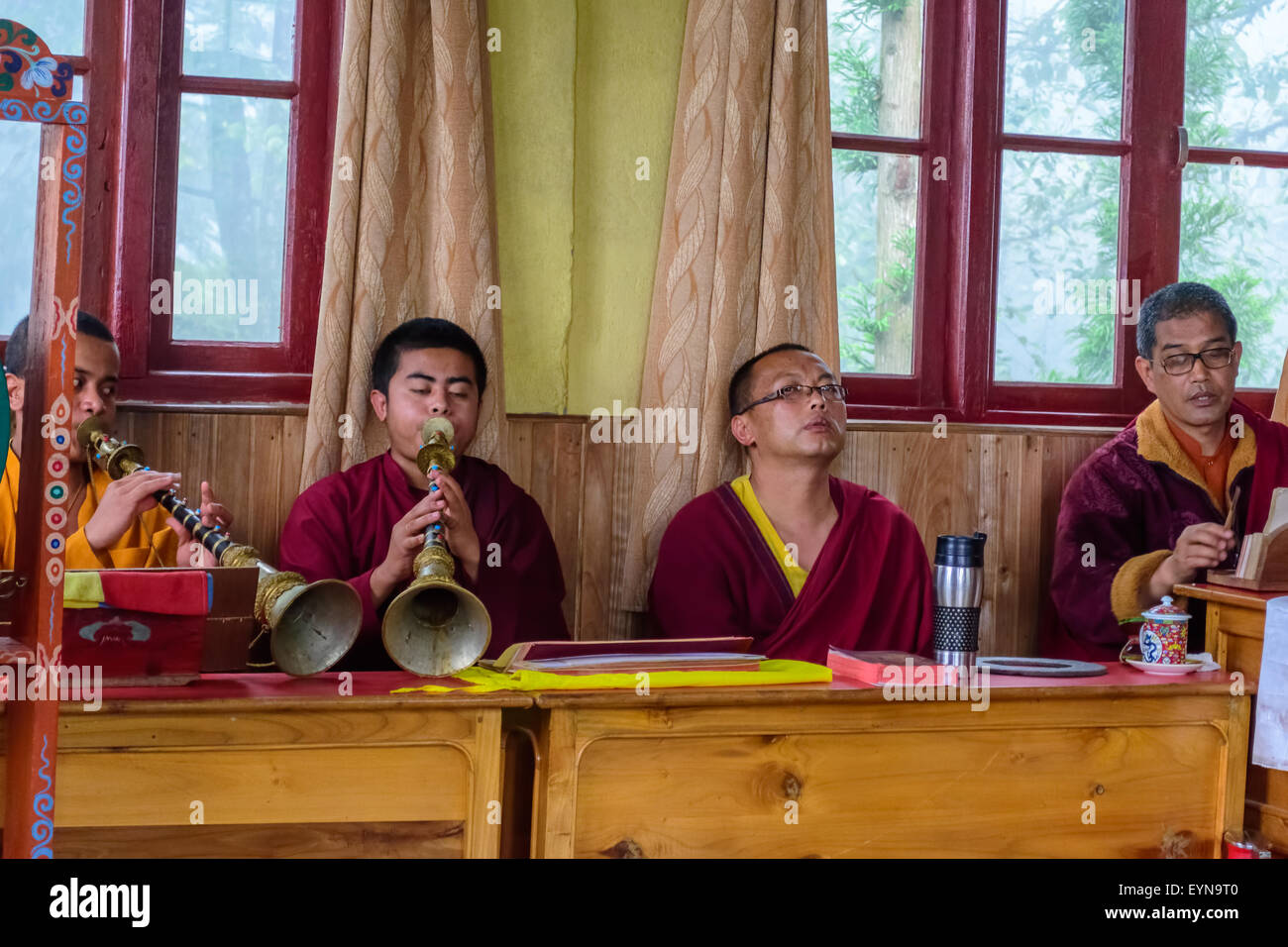 Four Buddhist priests, Lamas, praying inside a monastery in India, playing traditional flute, gong with copy space Stock Photo