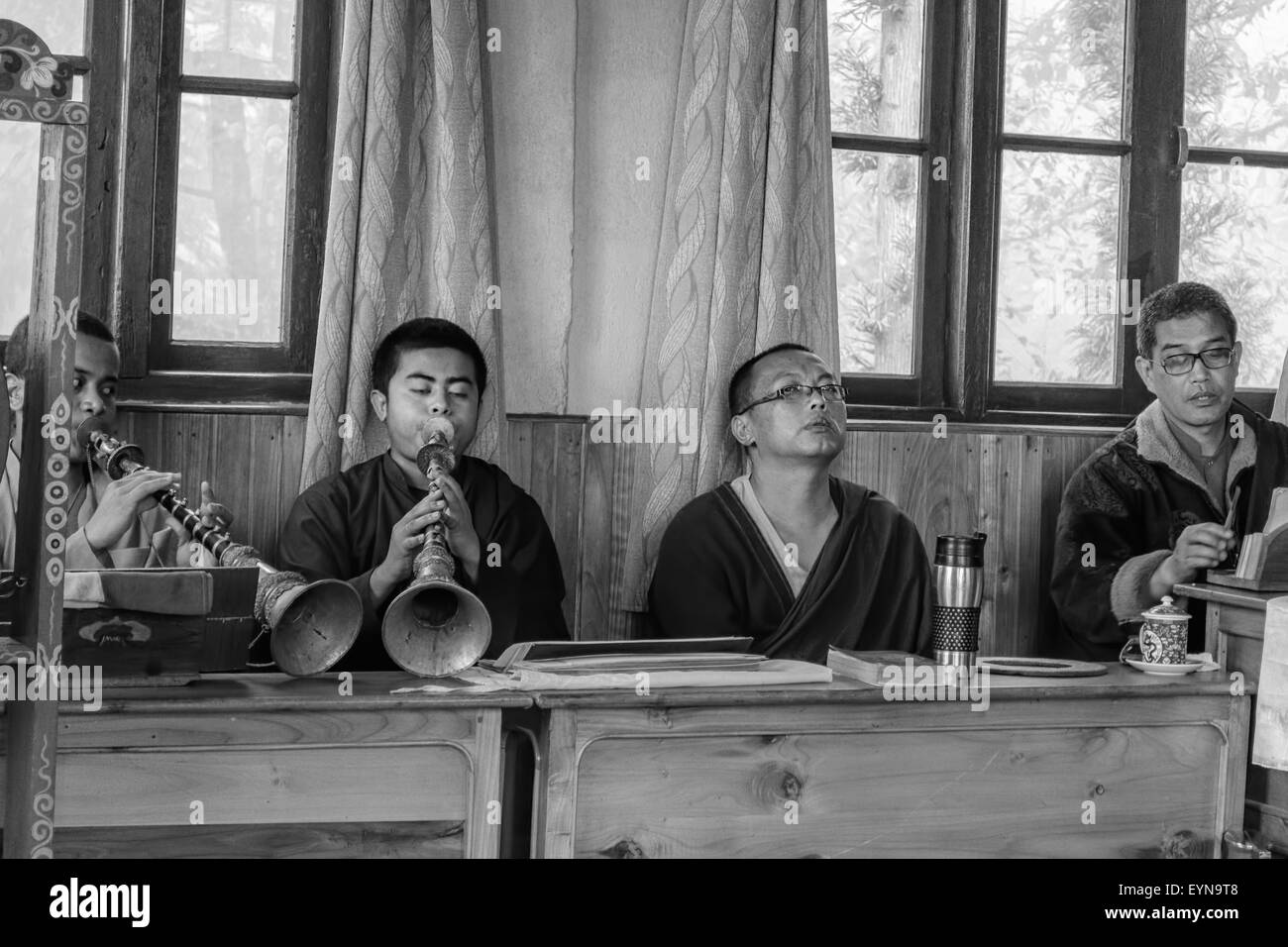 Buddhist priests, Lamas, praying inside a monastery in India, playing traditional flute, gong with copy space in black and white Stock Photo