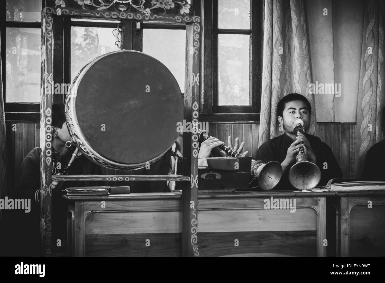 Buddhist priests, Lamas, praying inside a monastery in India, playing traditional flute, gong with copy space, black and white Stock Photo