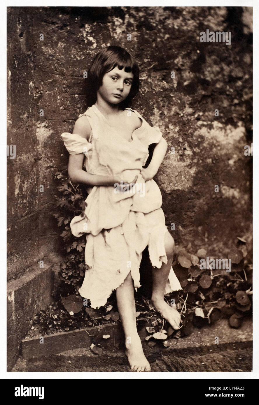 Alice Liddell (1852-1934) dressed as 'Beggar-Maid' in the deanery garden at Christ Church, Oxford University in 1858. This collodion photograph was taken by Charles Lutwidge Dodgson (1832-1898), better known as Lewis Carroll, and would have required over 40 seconds of exposure. 'The Beggar Maid' was a popular poem by Lord Alfred Tennyson (1809-1892) published in 1842, Tennyson thought the portrait one of the most beautiful photographs he had ever seen. See description for more information. Stock Photo