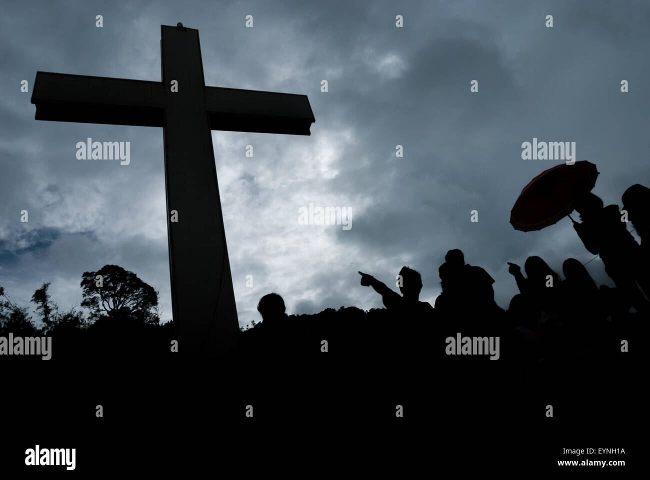 Silhouette of visitors and a tall Christian cross at Bukit Kasih (Hill of Love), a popular religious tourism destination in North Sulawesi, Indonesia. Stock Photo
