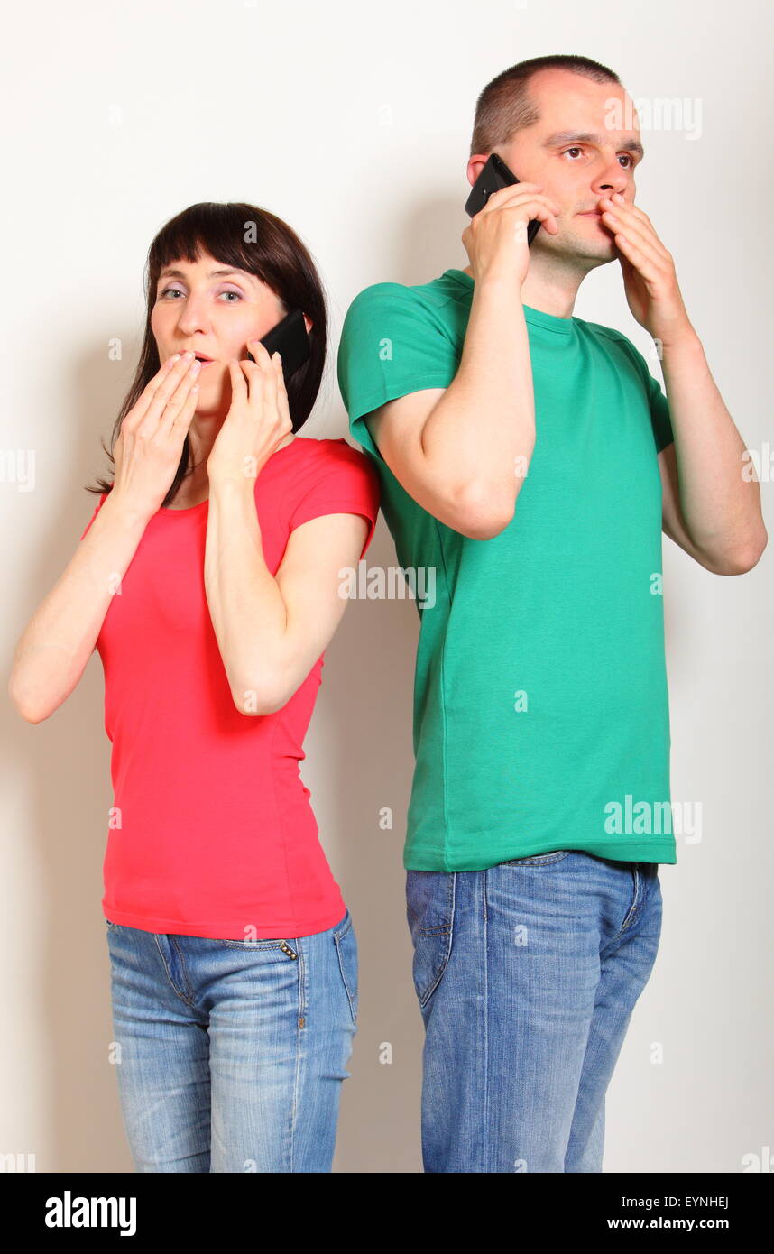 Shocked woman and man receive an unexpected message while talking on ...