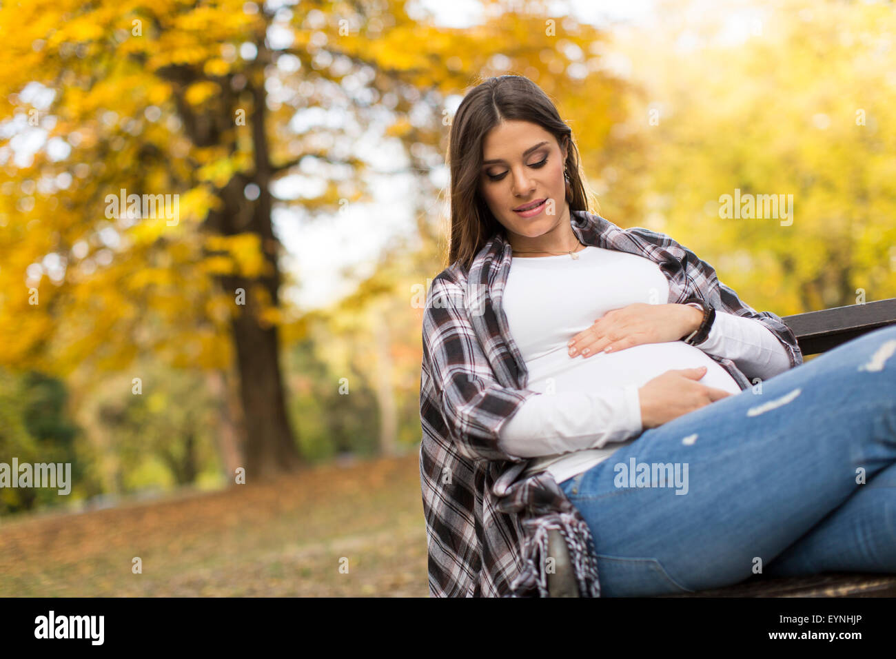 Young pregnant woman sitting in the autumn park Stock Photo - Alamy