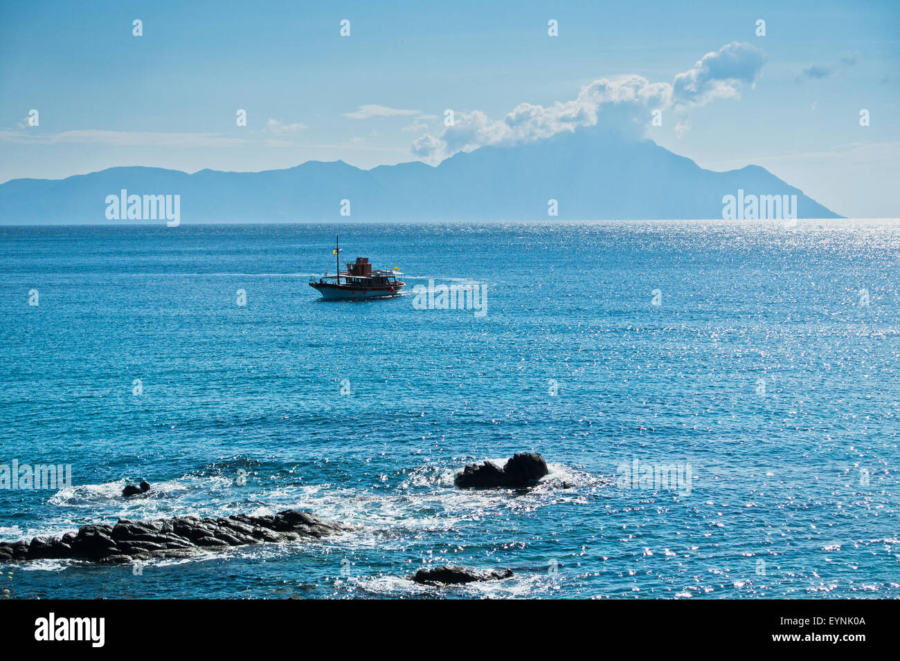 Ship is avoiding dangerous rocks near Sarti in Sithonia, mountain Athos in background Stock Photo